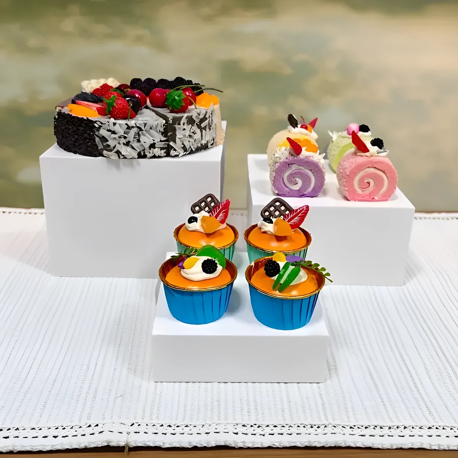 White and transparent plastic suit cube dessert display stands arranged in a tiered formation.