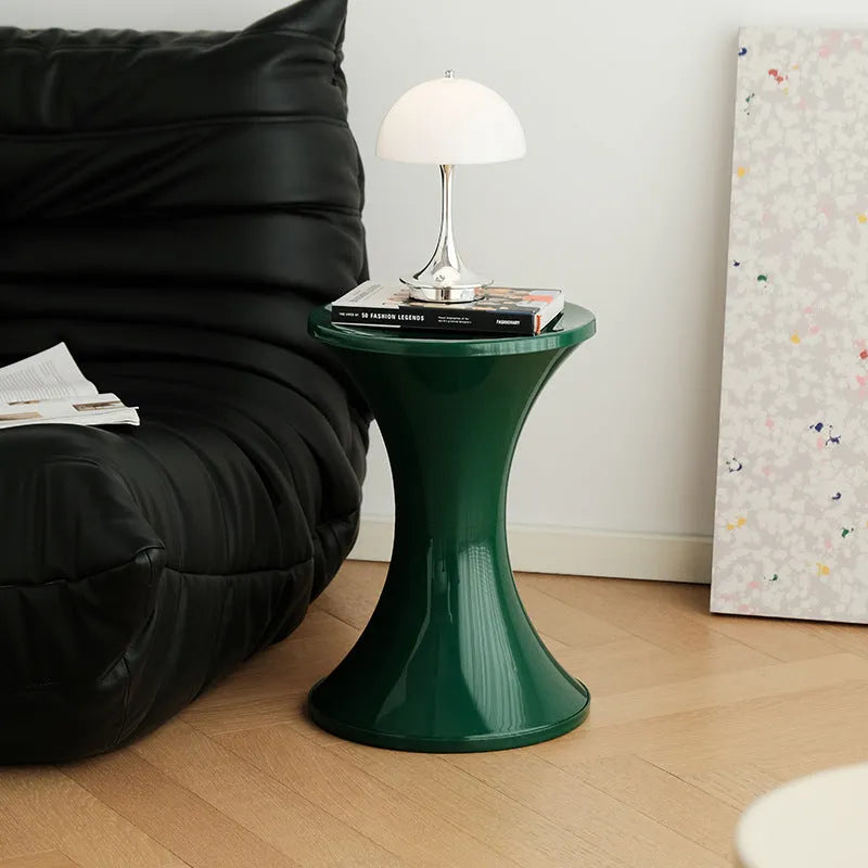 Creative hourglass-shaped plastic stool for changing shoes, shown in a green colour.
