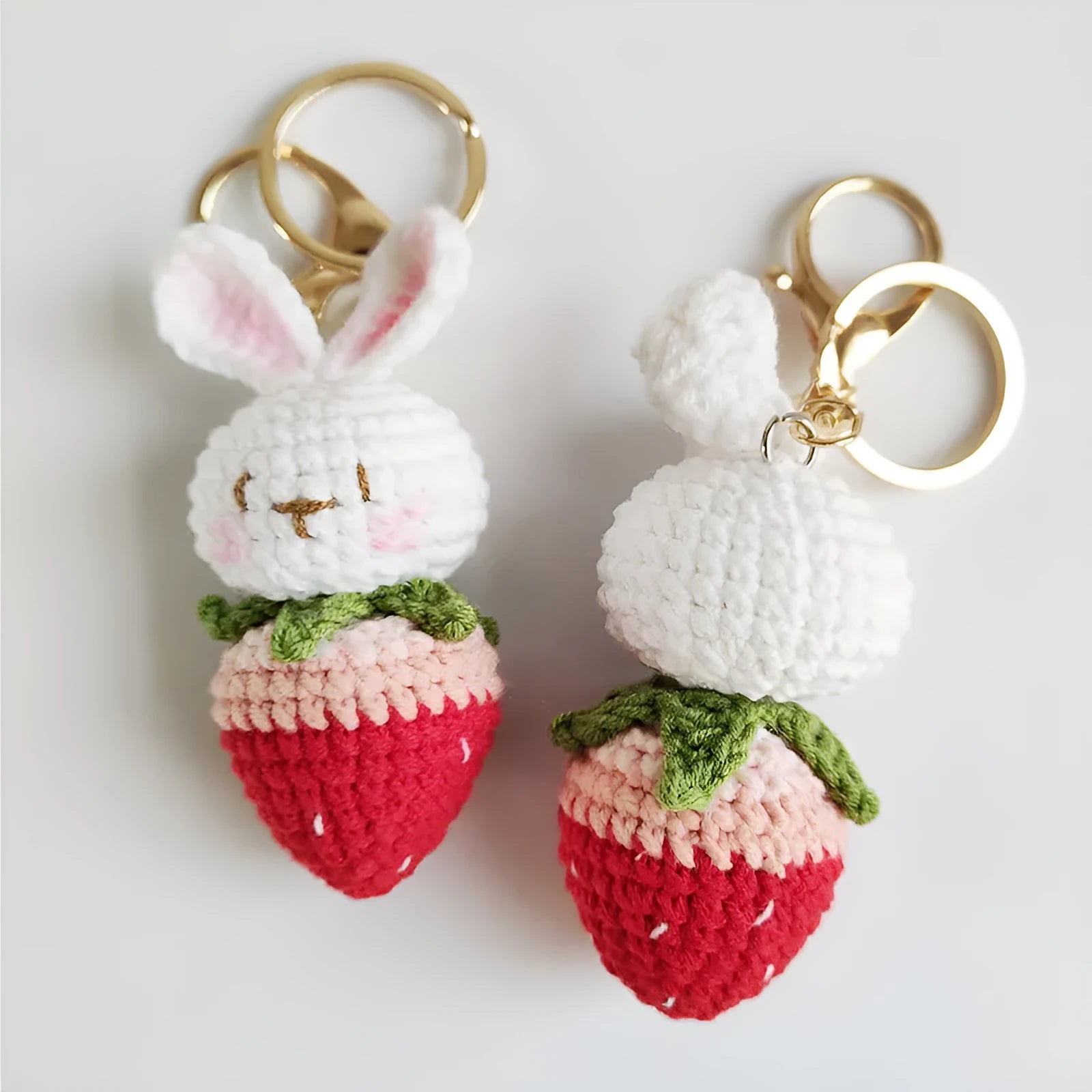 White hand-woven wire pendant showing a rabbit and strawberry design with an attached metal key.