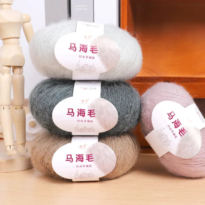 A ball of mohair yarn in a selected colour next to a hand-woven scarf example, showcasing the DIY kit.
