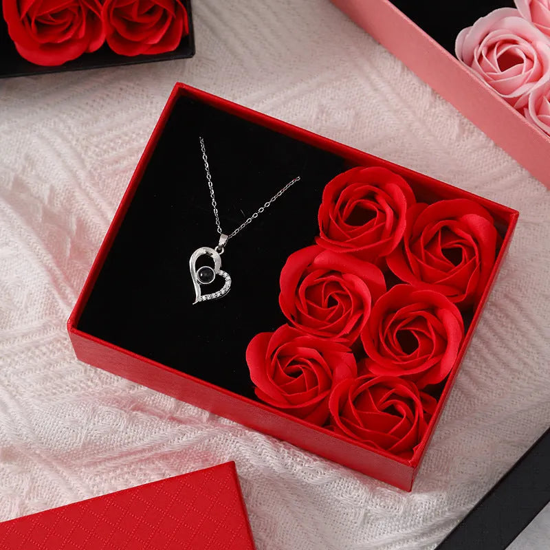 Red Korean-style jewellery gift box open to show six pink soap flowers, with a black handbag beside it.