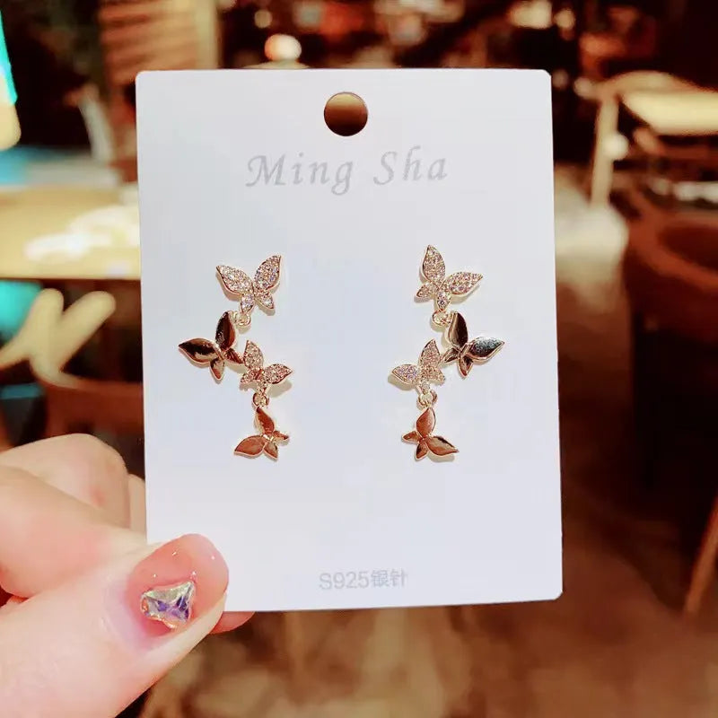Gold-coloured copper butterfly drop earrings showing four butterfly designs