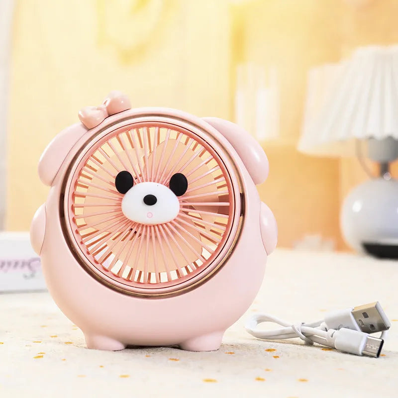 Cute dog-themed USB desktop electric fan on a wooden desk, showing three-speed buttons and a light pink puppy design.