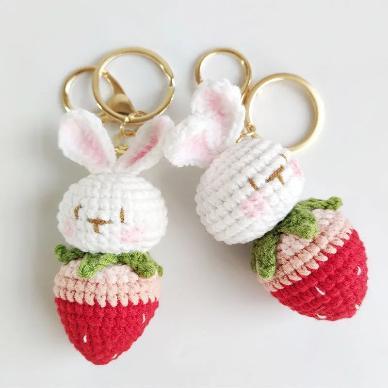 White hand-woven wire pendant showing a rabbit and strawberry design with an attached metal key.