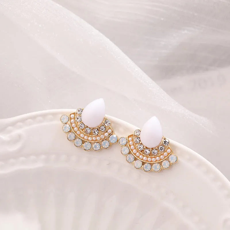 Women's silver geometric fan-shaped stud earrings with a central rhinestone on a white background.