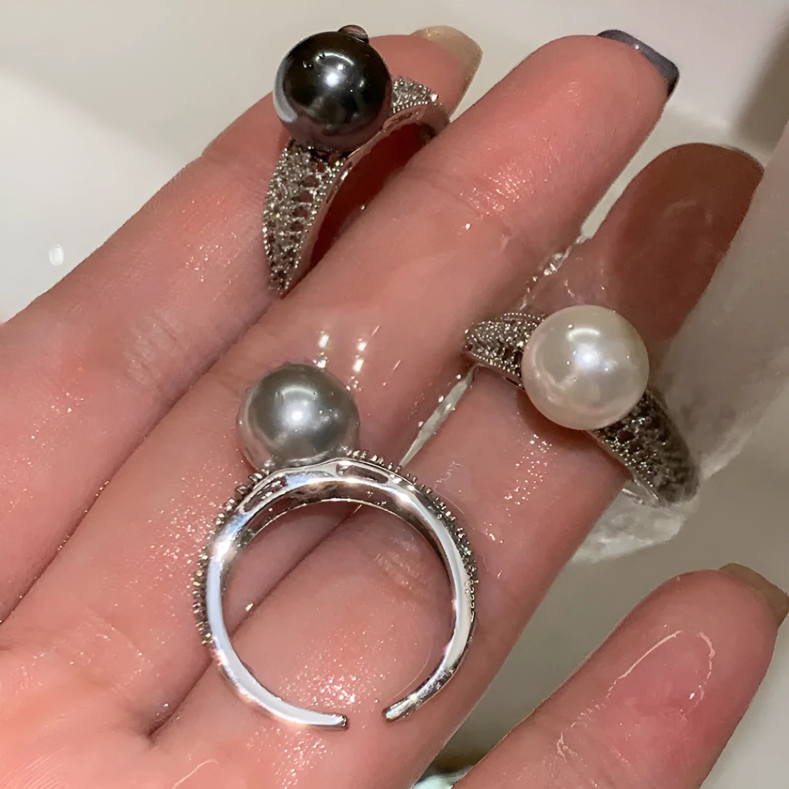 Geometric copper ring with black pearl and adjustable opening on a female index finger.