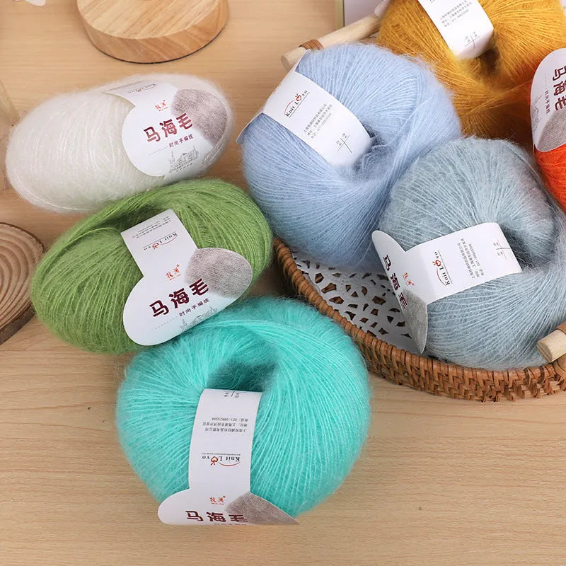 A ball of mohair yarn in a selected colour next to a hand-woven scarf example, showcasing the DIY kit.