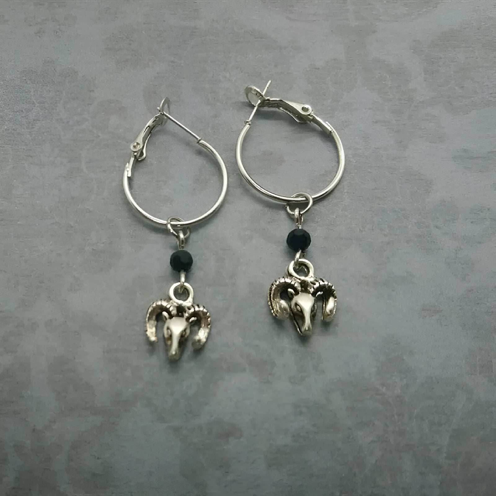 A pair of silver-coloured alloy round ring earrings featuring a Tibetan antelope design.