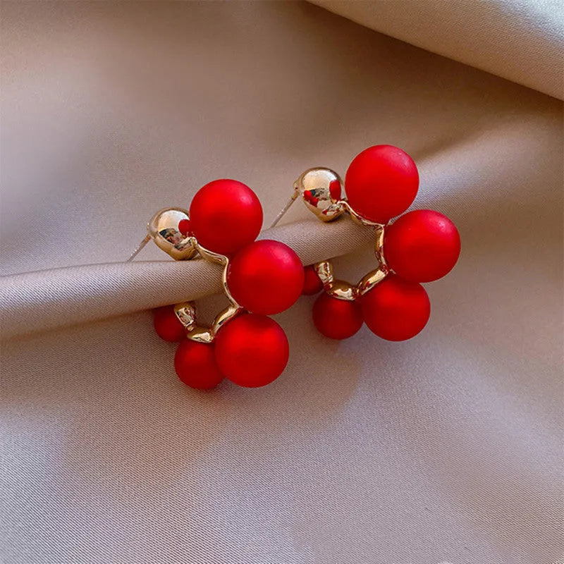 A pair of red bell-shaped alloy earrings for women on a plain background.