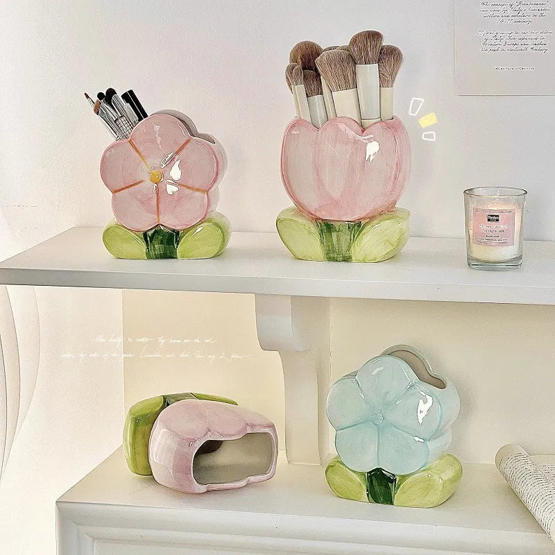 Ceramic pen holder box with floral decoration on a desk, holding pens.
