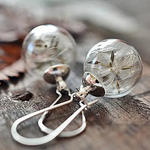 Close-up of a woman's ear wearing 16mm transparent glass ball dandelion seed earrings on a silver French hook.