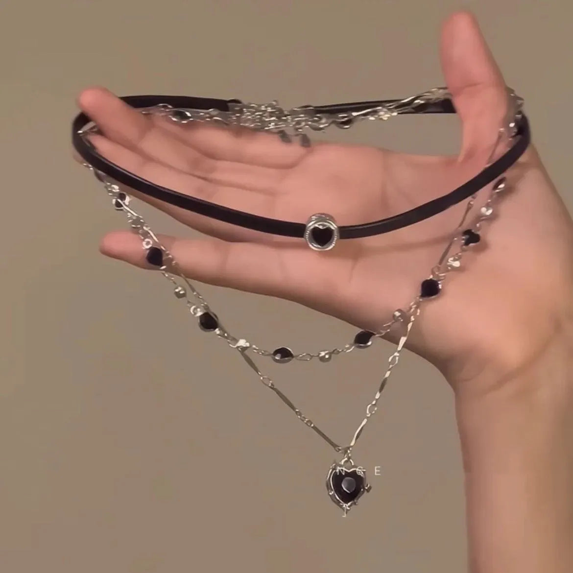 Close-up of a women's multi-layer heart necklace with a leather pendant on an adjustable alloy chain.