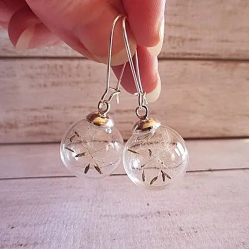Close-up of a woman's ear wearing 16mm transparent glass ball dandelion seed earrings on a silver French hook.