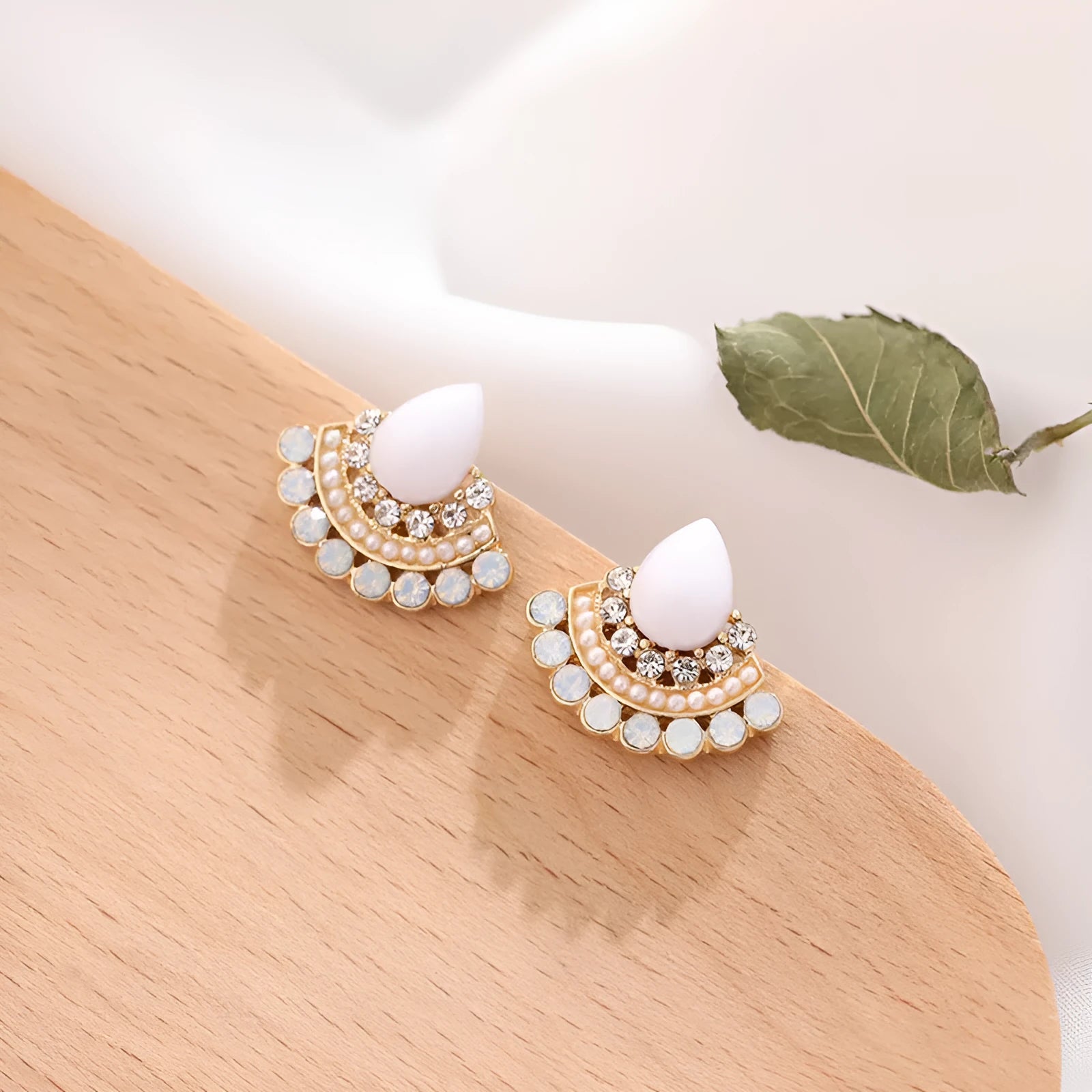 Women's silver geometric fan-shaped stud earrings with a central rhinestone on a white background.