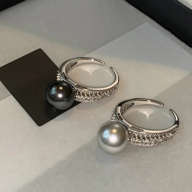 Geometric copper ring with black pearl and adjustable opening on a female index finger.