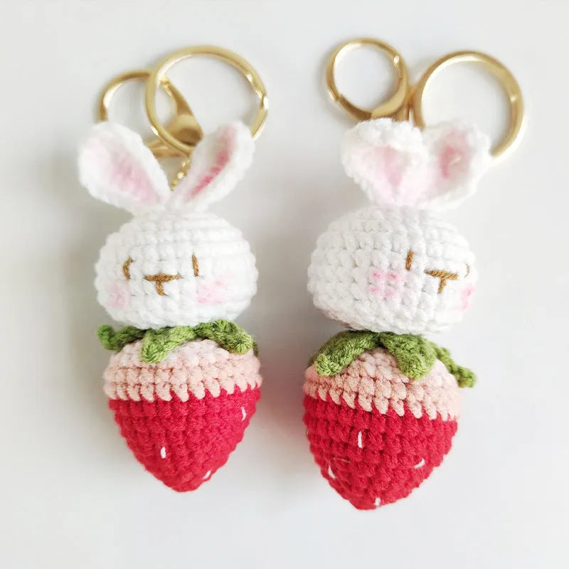 White hand-woven wire pendant showing a rabbit and strawberry design with an attached metal key.