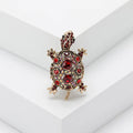 Close-up of a retro-style rhinestone turtle brooch in alloy, shown in blue, green and red colour options.