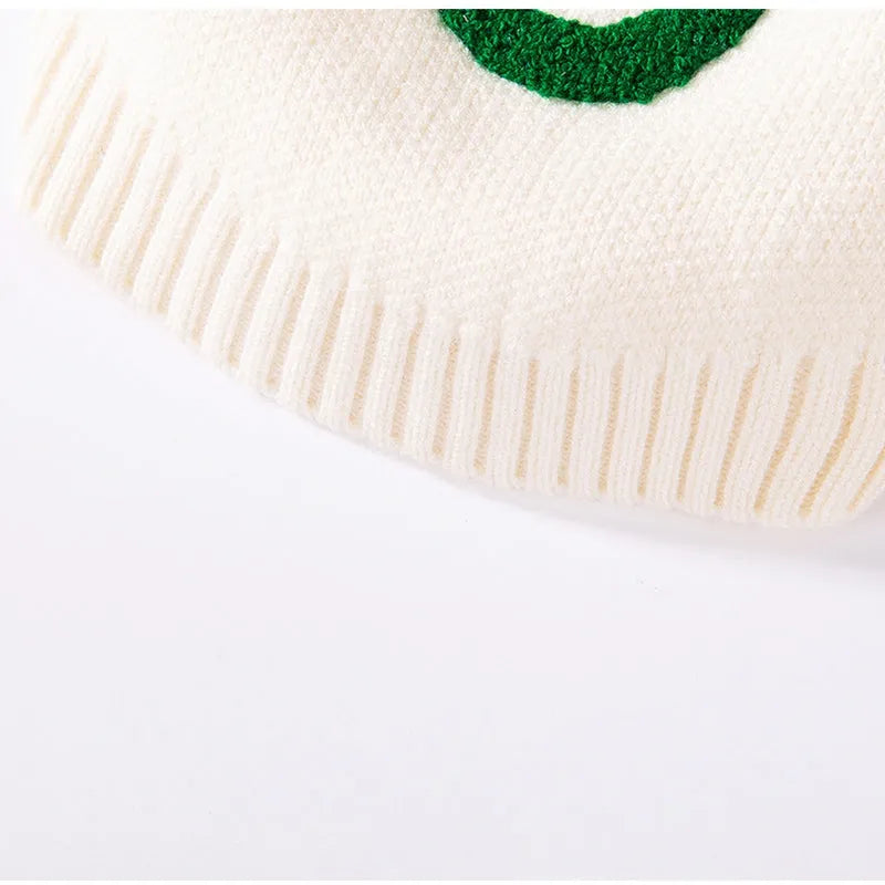 White knitted small dog sweater with rainbow Apple embroidery and green smiley face on a pet
