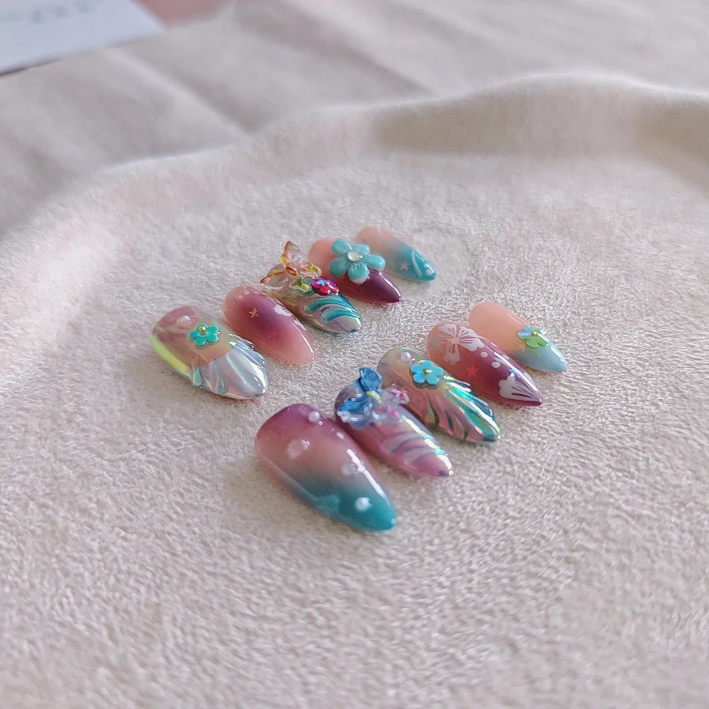 Handmade colourful nail art set with embossed small flower and butterfly sculptures for almond-shaped manicures.