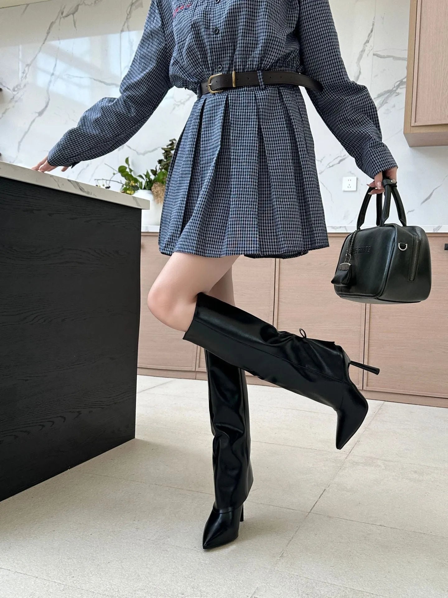 Black women's leg warmer boot covers with stiletto heel, showing flanging and leather stitch detail.
