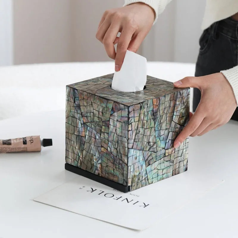 A black square shell storage box with a removable organiser insert on a coffee table.