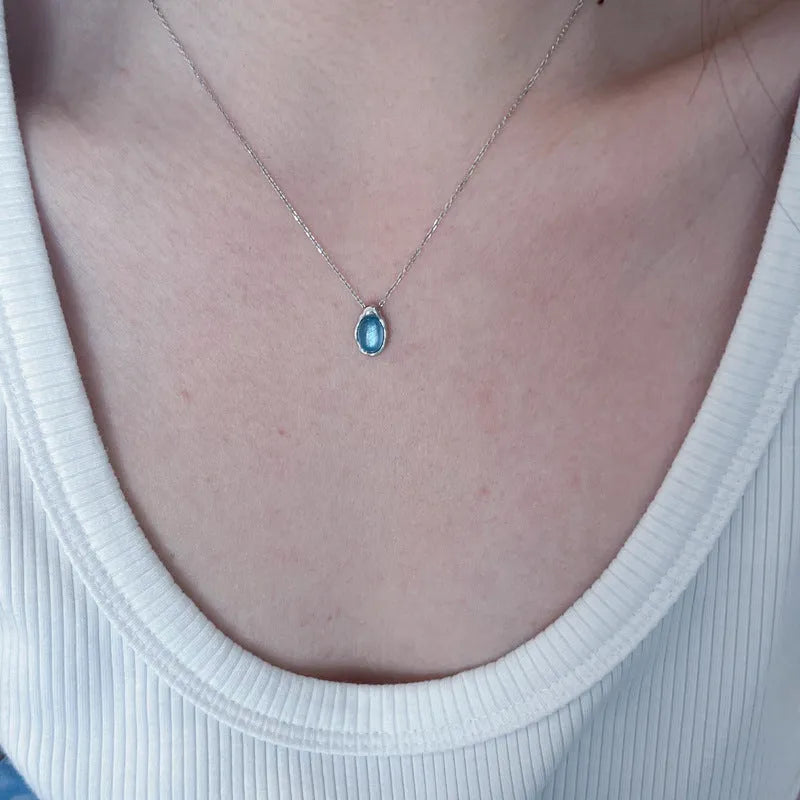 A women's navy blue geometric water drop pendant necklace with a platinum-colour finish on an adjustable cross chain.