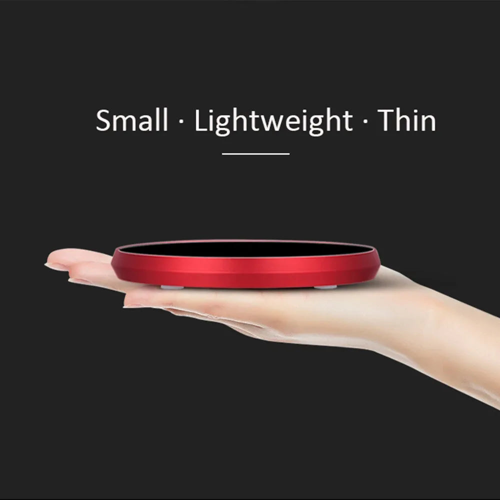 Black USB-powered beverage warming coaster with tempered glass top on a wooden desk