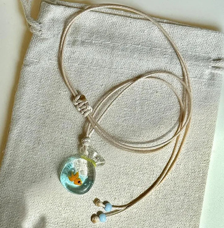 Women's necklace with coloured glaze joker pendant on a beige cotton linen clavicle chain.