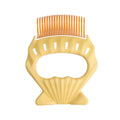 Green shell-shaped pet grooming brush with fine wire bristles on a white background.