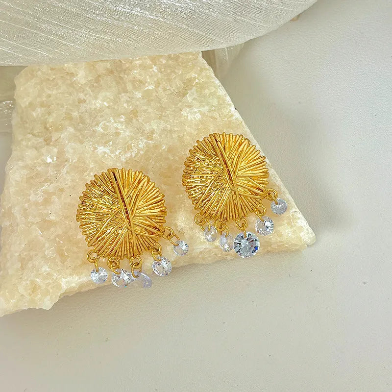 A pair of gold geometric metal earrings with round elements and an electroplated finish.