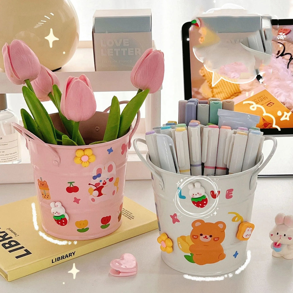 Round metal pen holder in a choice of colours including green, pink, and red on a wooden desk