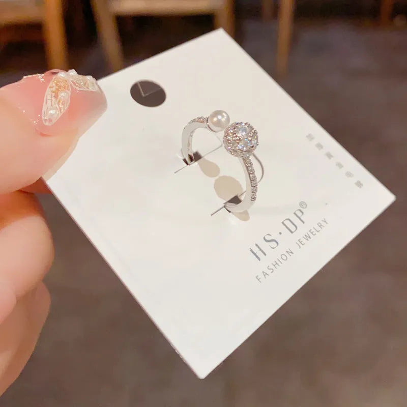 Minimalist open-end ring with round zircon stone on a geometric band in gold tone.
