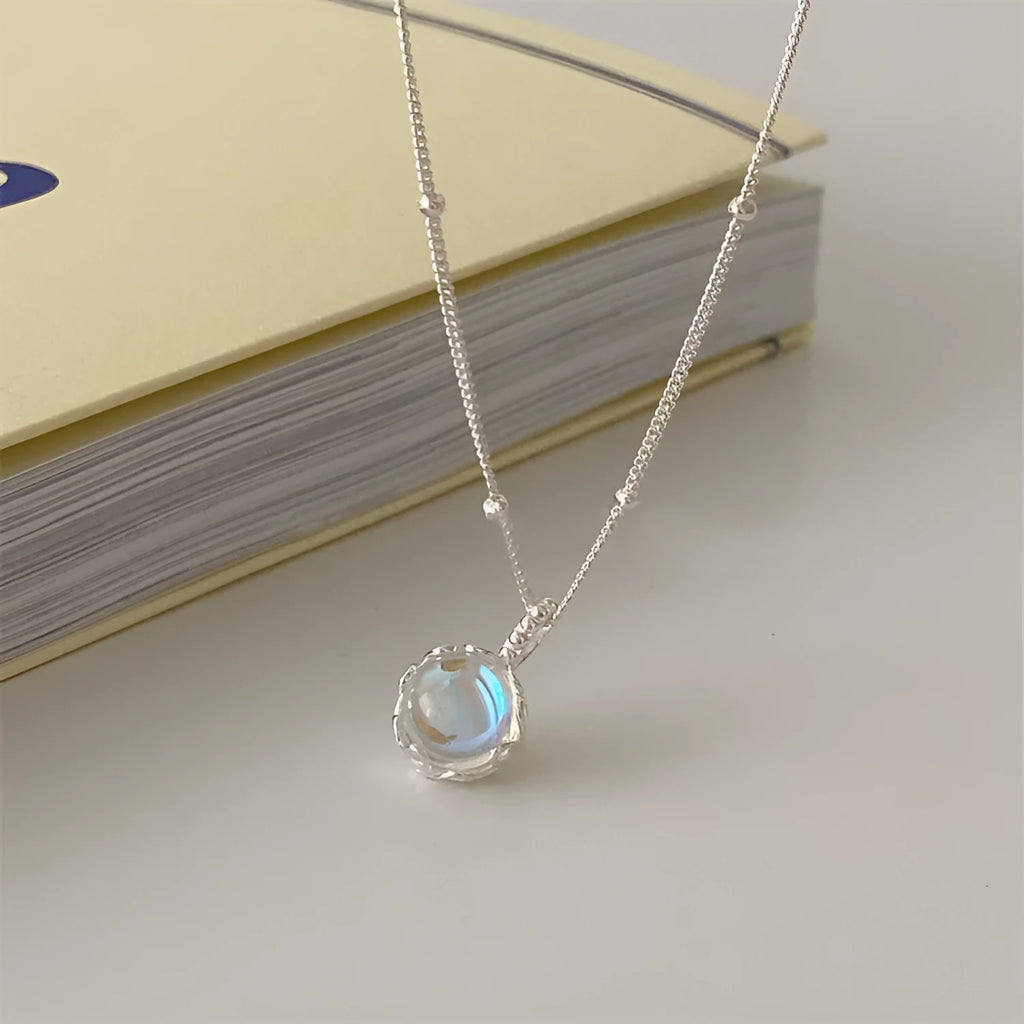 Close-up of a women's geometric 925 silver necklace with an adjustable curb chain, shown on a dark background.