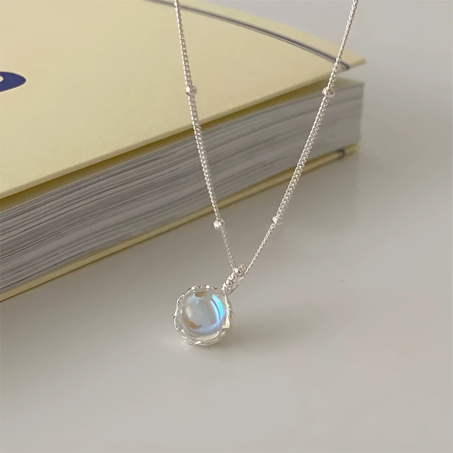 Close-up of a women's geometric 925 silver necklace with an adjustable curb chain, shown on a dark background.