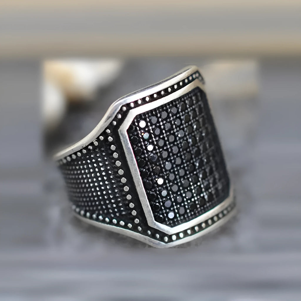 Black alloy ring with copper inlay and zircon stone, shown on a finger, size range 7 to 13.