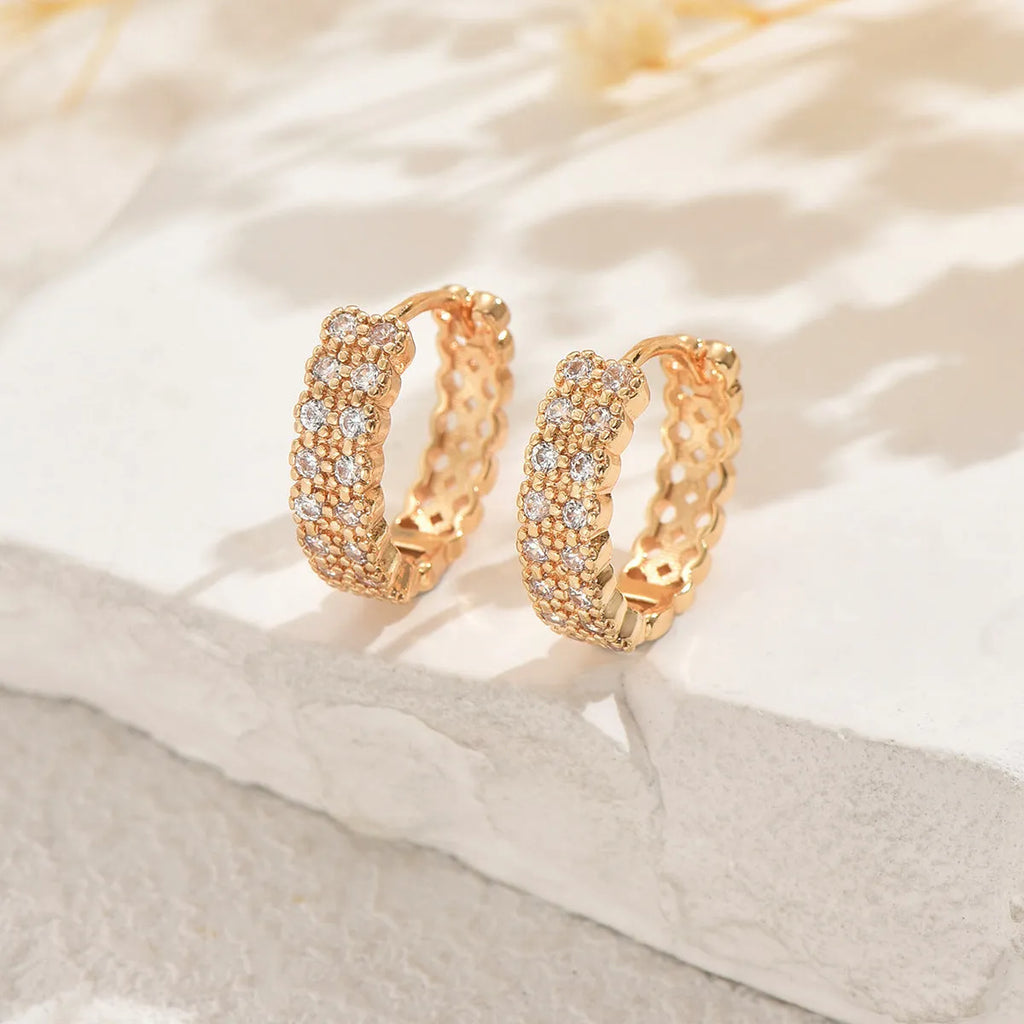 A pair of geometric pattern copper ear studs with round, dot, and ring decorative details.