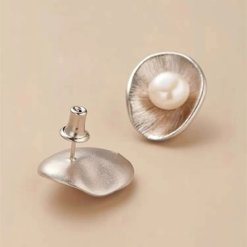 A pair of geometric sterling silver ear studs with pearl accents and a gold electroplated finish.