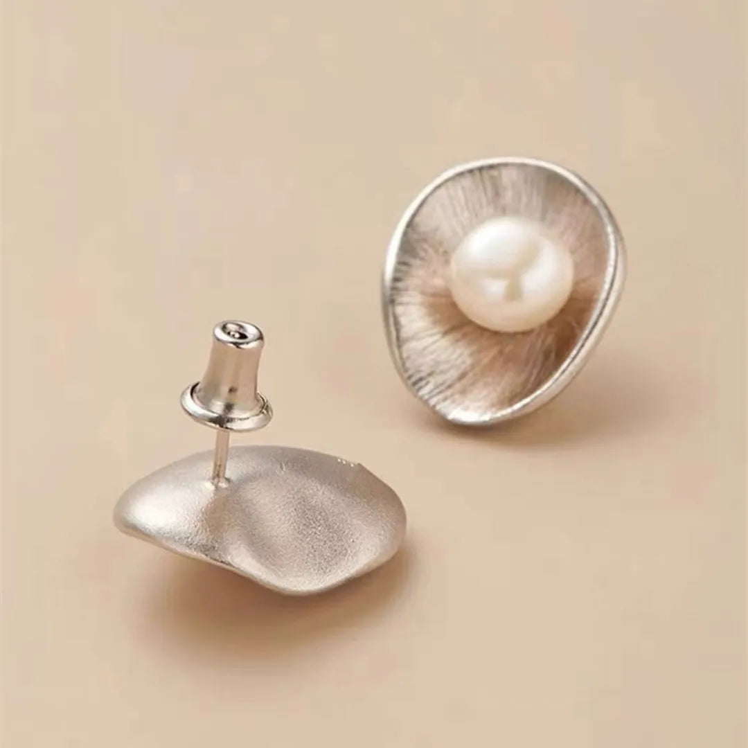 A pair of geometric sterling silver ear studs with pearl accents and a gold electroplated finish.