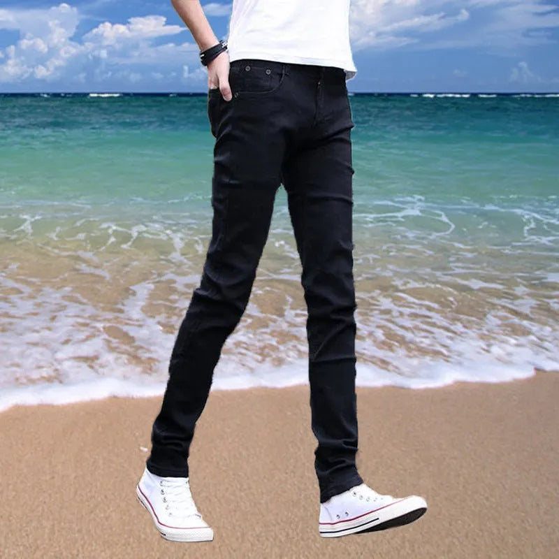 Thin men's loose skinny casual jeans in pure black with low waist, cropped leg, small leg opening, and zip fly.