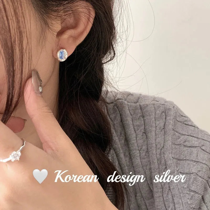 S925 sterling silver earrings with oval blue diamond heart-wrapped geometric design and electroplated silver finish