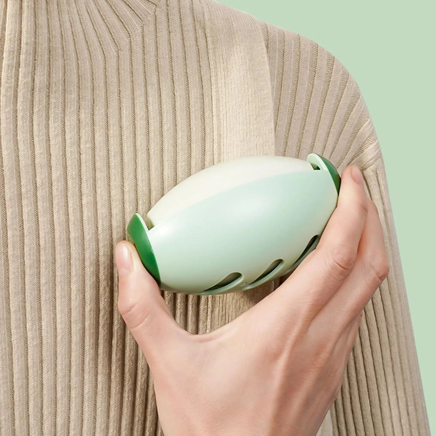 Green and white washable reusable gel lint roller ball for pet hair removal on fabric.