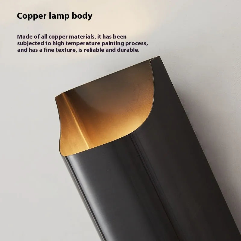 Minimalist copper wall lamp in black gold finish mounted beside a bed