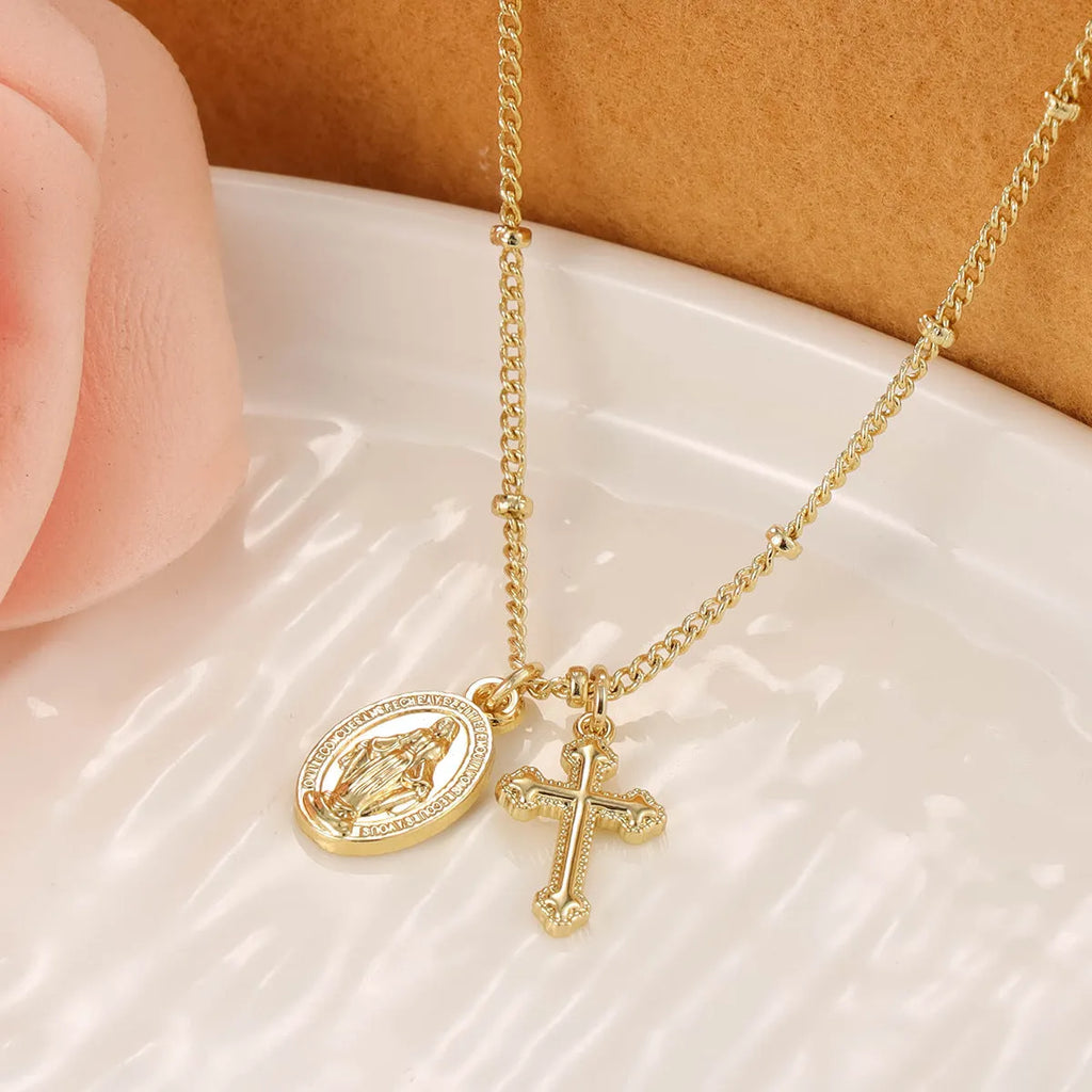 Gold geometric cross pendant necklace with Virgin Mary centre on a model.