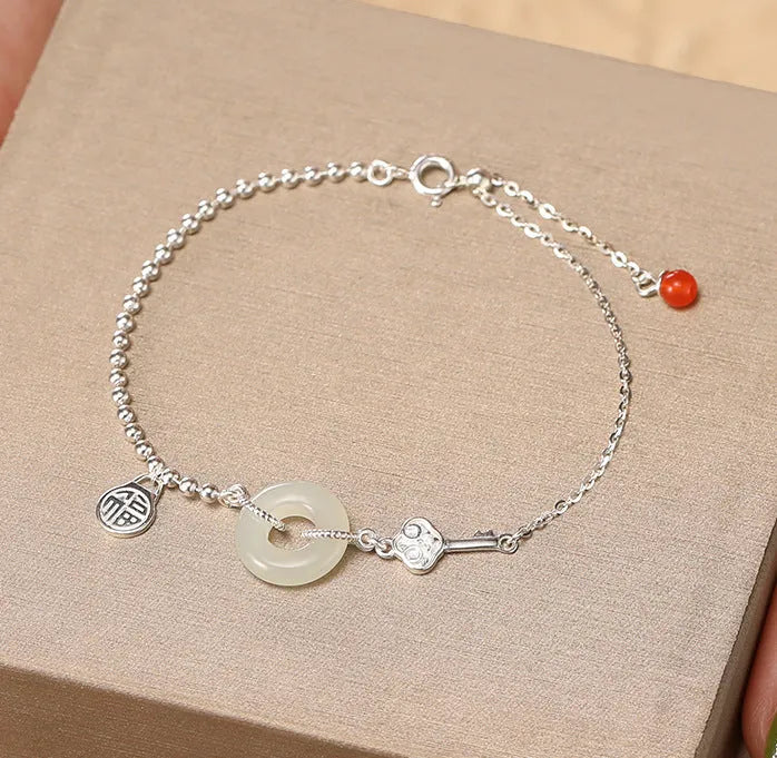 Women's Chinese style silver bracelet with a Hetian jade stone and intricate Peace Buckle design.