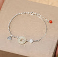 Women's Chinese style silver bracelet with a Hetian jade stone and intricate Peace Buckle design.