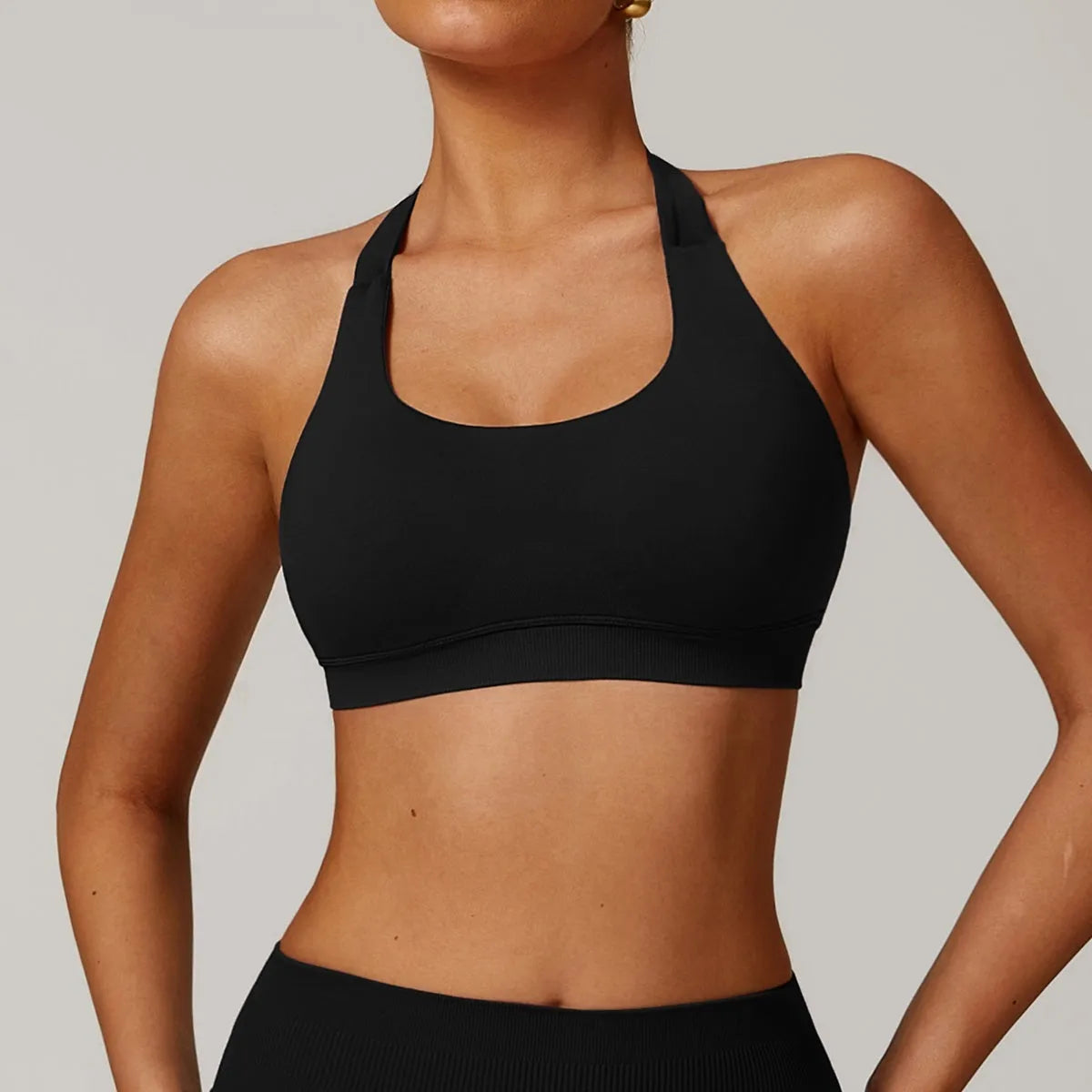 Women's black halter-style yoga sports bra with medium support and built-in chest pads.