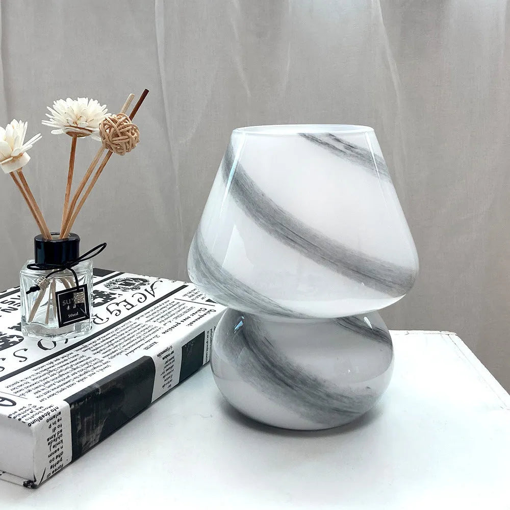 Handmade glass mushroom table lamp in Earth colour on a wooden bedside table with a soft glow