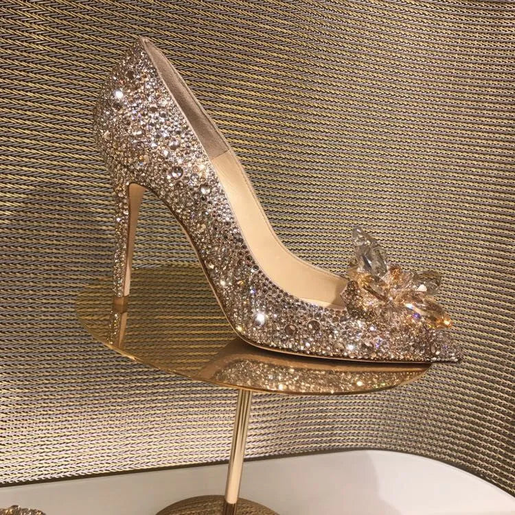 Women's gold stiletto high heel with pointed toe, rhinestone decorations, and a bow.