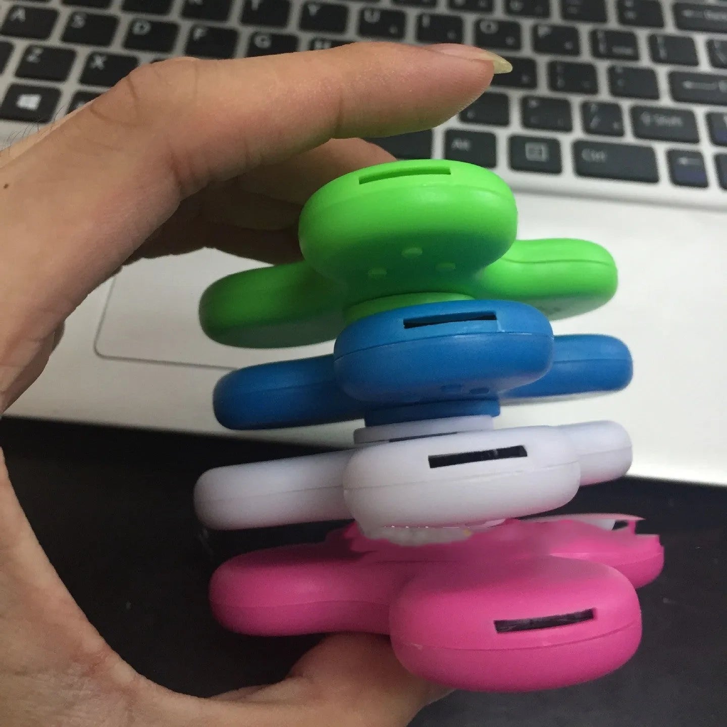 A square blue Bluetooth speaker and MP3 player with an integrated fidget spinner, showing button controls.