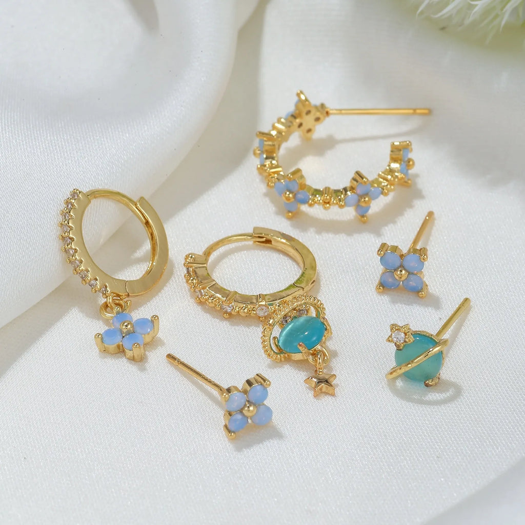 Gold and silver flower shaped stud earrings with a central zircon stone, showing front and back.